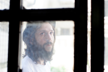 young bearded man behind a window