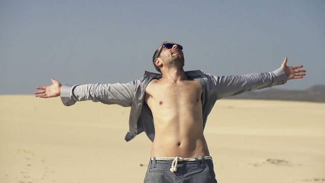 Young man with wide open arms on desert enjoying sunny day
