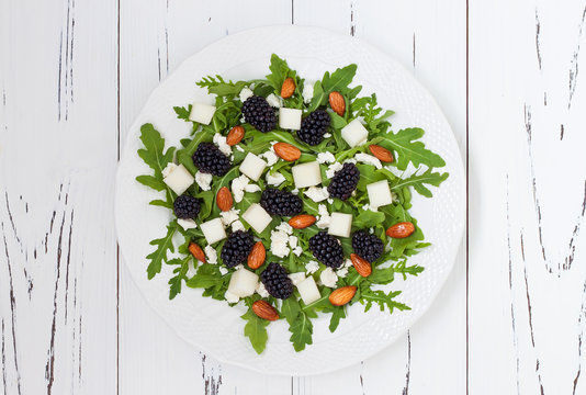 Summer green salad with arugula, melon, blackberries, almonds and feta cheese