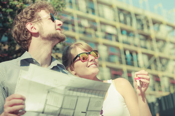 Couple on front of new house with blueprint project