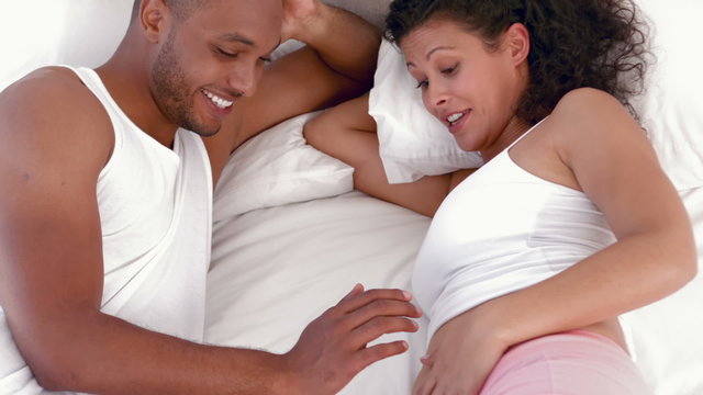 Pregnant couple relaxing on bed