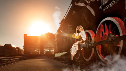 Woman in the vintage dress is sitting on the locomotive's wheel © diter