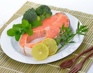 fresh salmon fillet with vegetables and lemon slices.