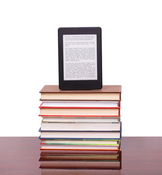 electronic book reader and pile old books on wood desk table
