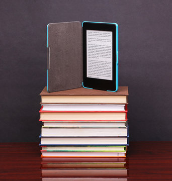 electronic book reader and pile old books on wood desk table