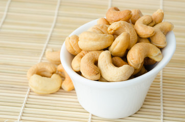 Cashew nuts with salt in white bowl.