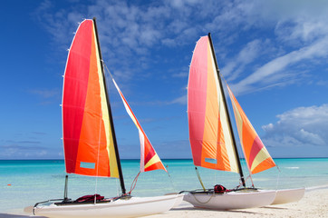 Two catamarans with its colorful sails wide open on cayo Santa M