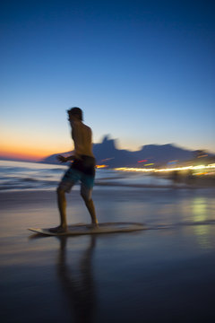 Action silhouette of Brazilian riding skimboard on Ipanema Beach Rio de Janeiro Brazil at sunset