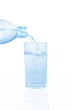 Pouring water on a glass on white background. This has clipping