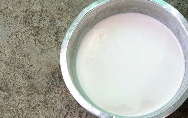 Coconut milk in a stainless steel bowl on cement background.