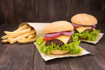Cheeseburger with french fries on wooden background
