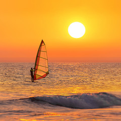 Windsurfer silhouette at sea sunset. Summertime watersports  © EMrpize