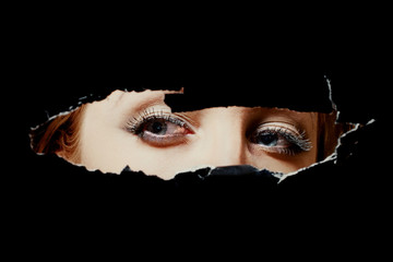 Eyes of a young woman peeping through hole - 88908283