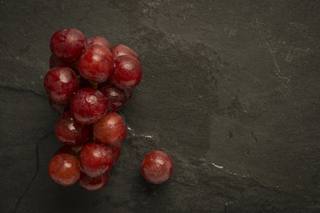 Red grapes with water droplets on slate