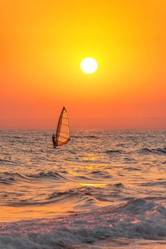 Windsurfer silhouette at sea sunset. Summertime watersports 
