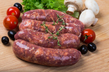 uncooked raw sausages on wooden board