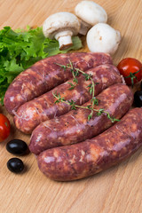 uncooked raw sausages on wooden board