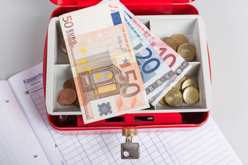 Geldkassette, Bargeld und ein Kassenbuch für Einnahmen und Ausgaben eines Unternehmers