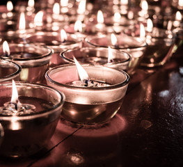 vintage filter,Pray candle glass on wood table in chinese temple