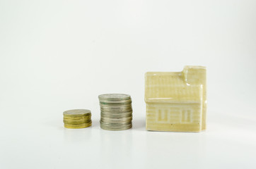 Stacked Malaysian Ringgit coins leading to miniature dream house, isolated on white background