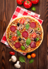 Italian pizza with pepperoni, tomatoes, olives and basil
