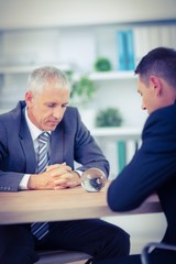 Two businessmen watching crystal ball