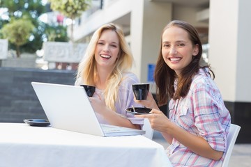 Happy women friends smiling at camera with cups of coffee
