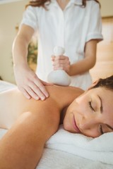 Obraz na płótnie Canvas Young woman getting herbal compress massage