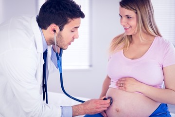 Doctor talking to smiling pregnant patient while examining her