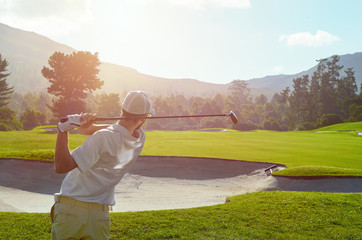 golf man takes a swing over bunker