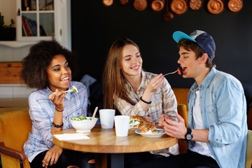 Cheerful multiracial friends eating in a cafe