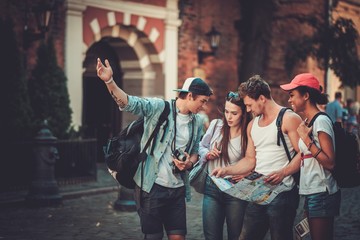 Multiracial friends tourists with map in an old city