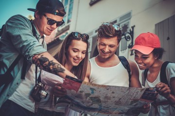 Multiracial friends tourists with map in an old city