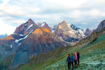 People observing mountain scenery.
Large group of men staying on grassy trail looking side...