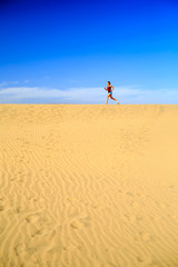Young woman running on sand desert dunes