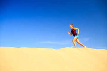 Young woman running on sand desert dunes