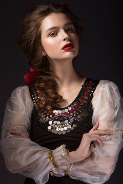 Beautiful Russian girl in national dress with a braid hairstyle and red lips. Beauty face. Picture taken in the studio on a black background.