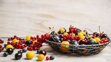 Different berries in a basket on a white wooden table 