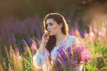 Beautiful young girl, holding lavender in a field on sunset. wal