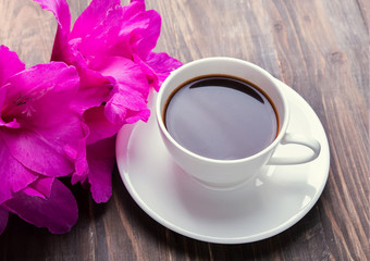 Cup of black coffee and pink flowers