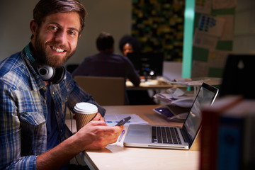 Fototapeta premium Office Worker With Coffee At Desk Working Late On Laptop