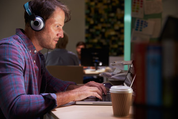 Male Office Worker With Coffee At Desk Working Late