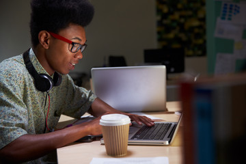 Office Worker With Coffee At Desk Working Late On Laptop