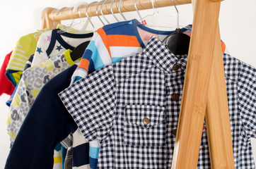 Dressing closet with clothes arranged on hangers.Colorful wardrobe of newborn,kids, toddlers, babies full of all clothes.Many t-shirts,pants, shirts,blouses, onesie hanging