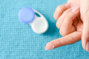 Soft contact lens on a woman's fingertip, with open case in the background