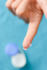 Naklejka premium Soft contact lens on a woman's fingertip, with open case in the background