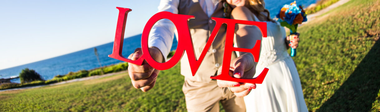 bride with groom holding bouquet and word love