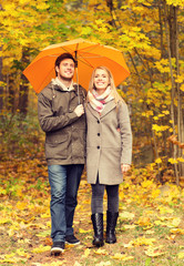 Fototapeta premium smiling couple with umbrella in autumn park