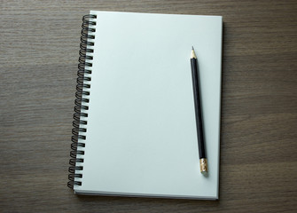 blank spiral notebook and pencil on dark wood background