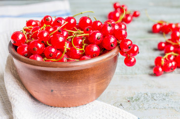 fresh red currants in brown clay piala on a wooden background
